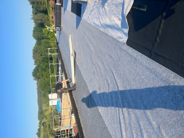 Mitarbeiter beim Verlegen von Schutzvlies auf einem Flachdach